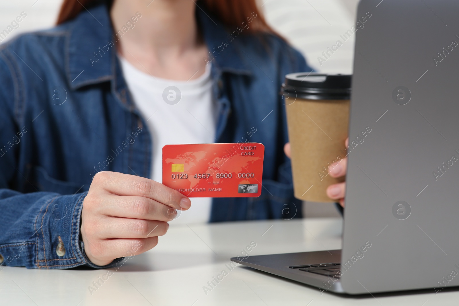 Photo of Woman with credit card using laptop at white table, closeup