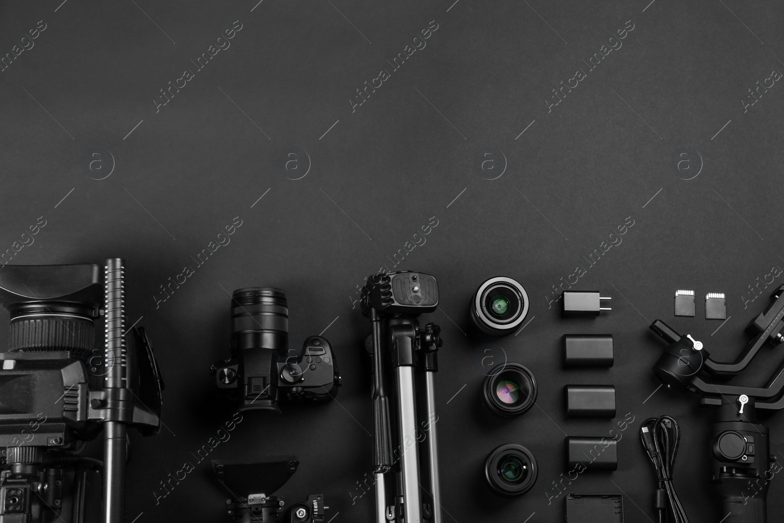 Photo of Flat lay composition with video camera and other equipment on black background. Space for text