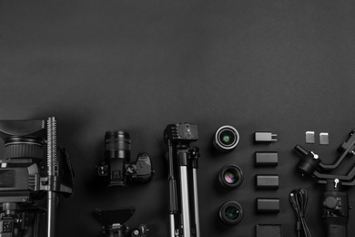 Photo of Flat lay composition with video camera and other equipment on black background. Space for text