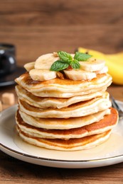 Photo of Tasty pancakes with sliced banana on wooden table, closeup