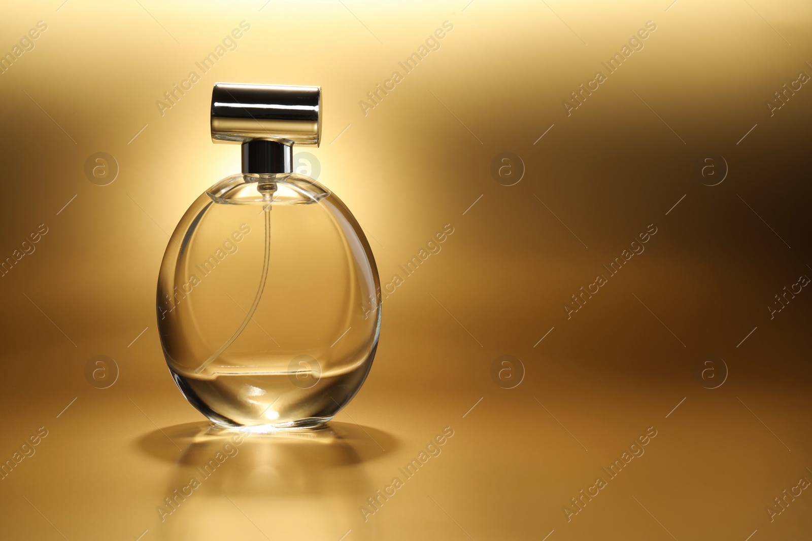 Photo of Luxury women's perfume. Sunlit glass bottle on golden background, space for text