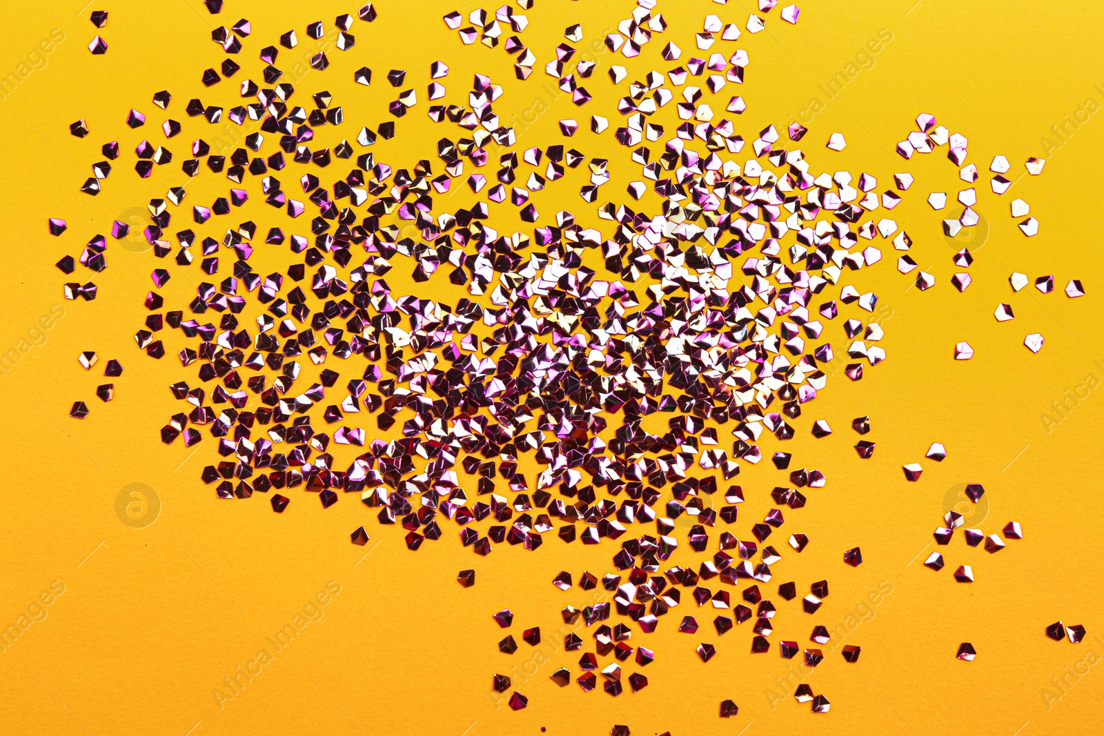 Photo of Shiny bright violet glitter on yellow background, flat lay