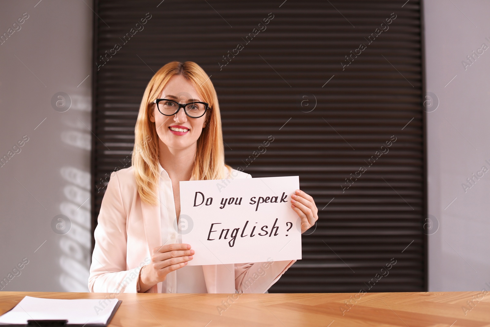 Photo of Teacher holding sheet of paper with words Do You Know English? in class