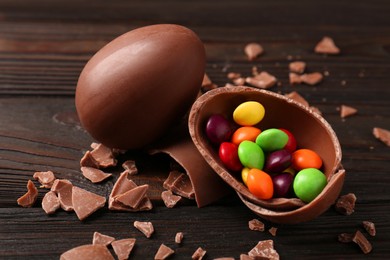 Photo of Broken and whole chocolate eggs with sweets on wooden table