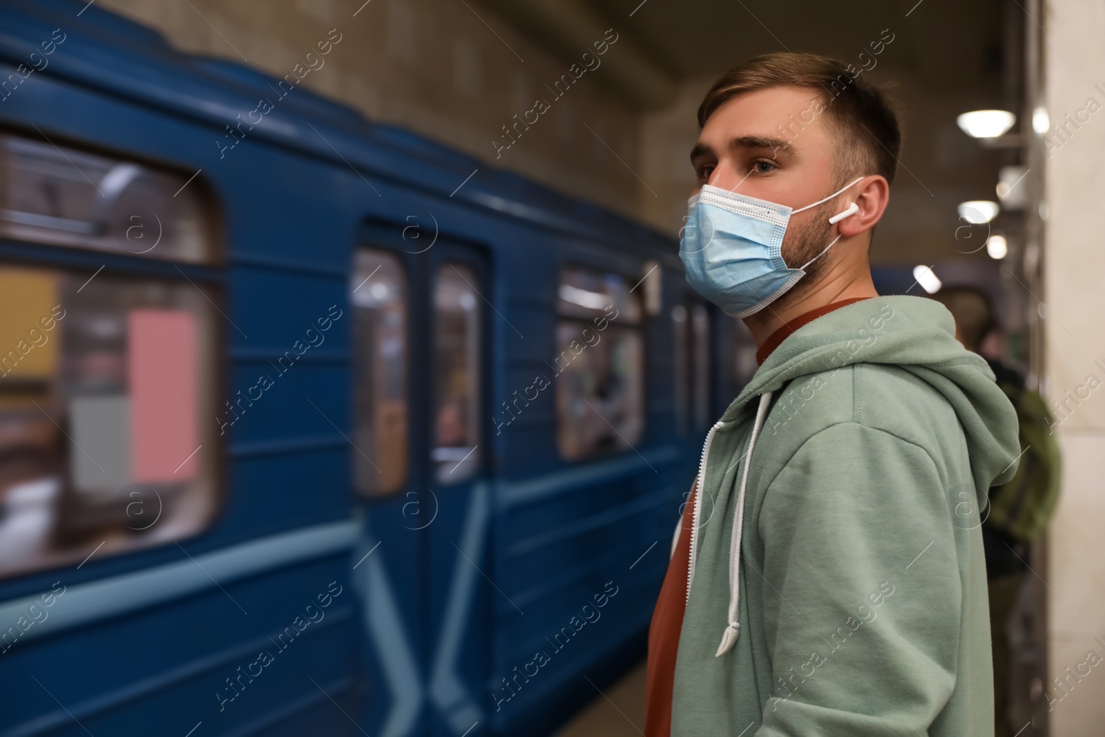 Photo of Young man in protective mask at subway station, space for text. Public transport