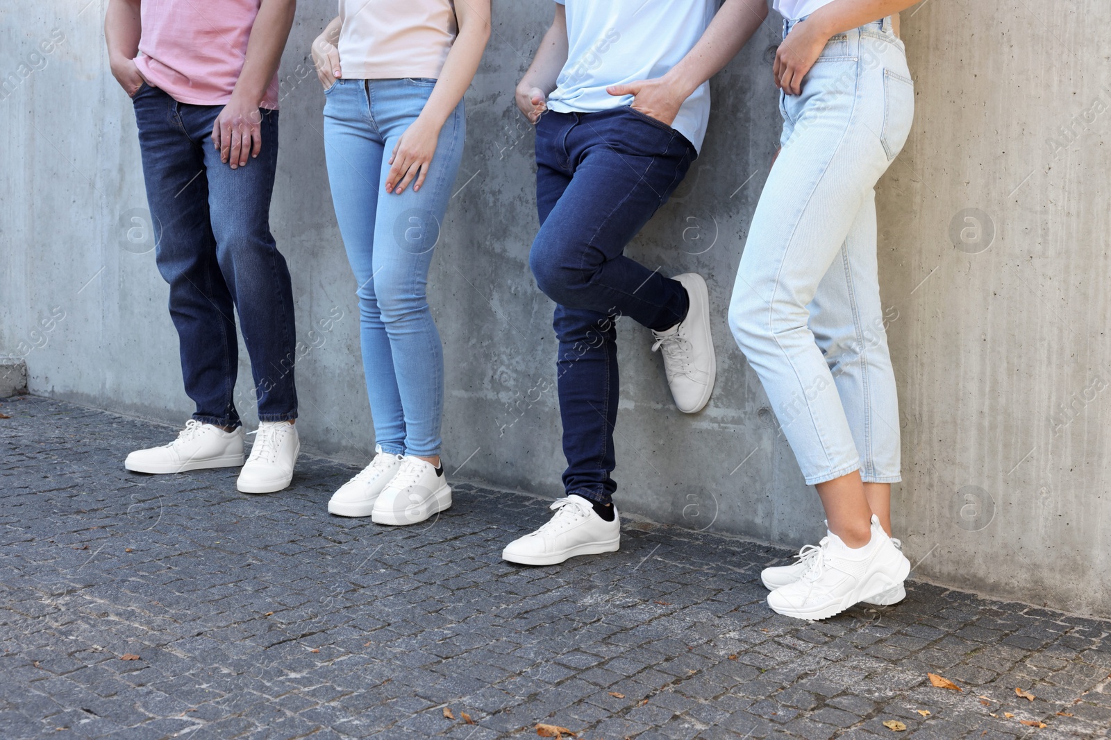 Photo of Group of people in stylish jeans near grey wall outdoors, closeup