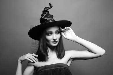 Mysterious witch wearing hat on dark background. Black and white effect