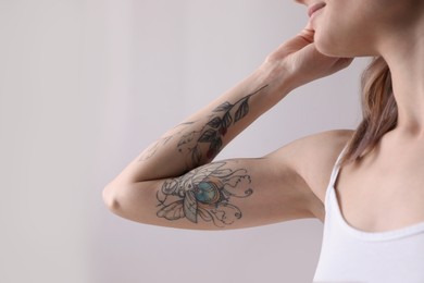 Photo of Beautiful woman with tattoos on arm indoors, closeup