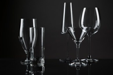 Empty glasses for different drinks on dark background