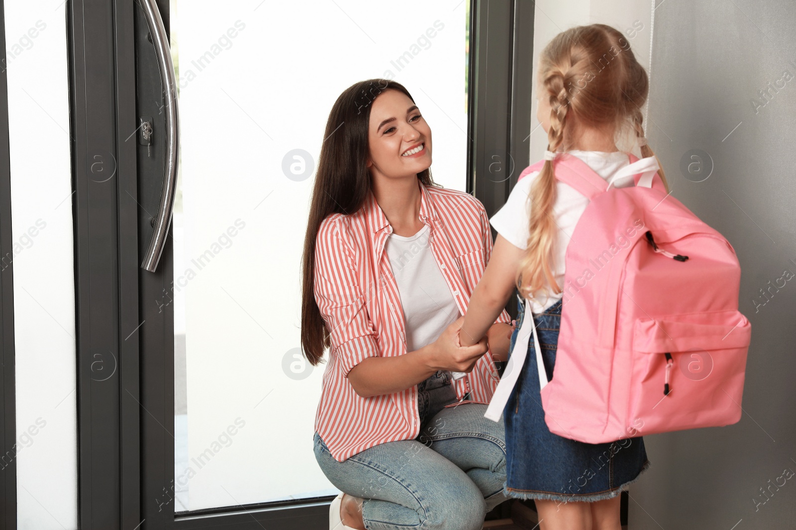 Photo of Happy mother and little child with school bag at door