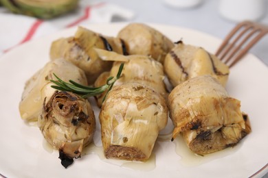Photo of Delicious pickled artichokes with rosemary on plate, closeup