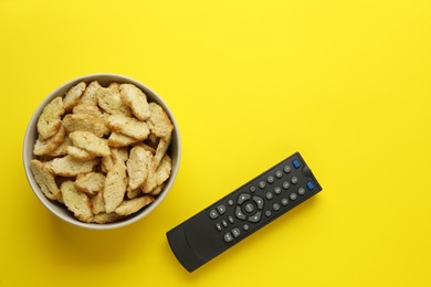 Photo of Remote control and rusks on yellow background, flat lay