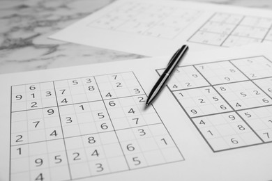 Photo of Sudoku and pen on table, closeup view