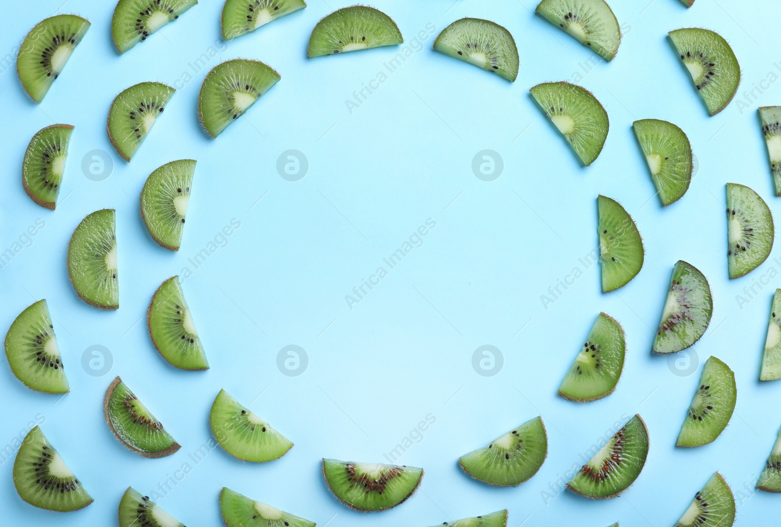 Photo of Frame of fresh ripe kiwi slices on light blue background, flat lay. Space for text
