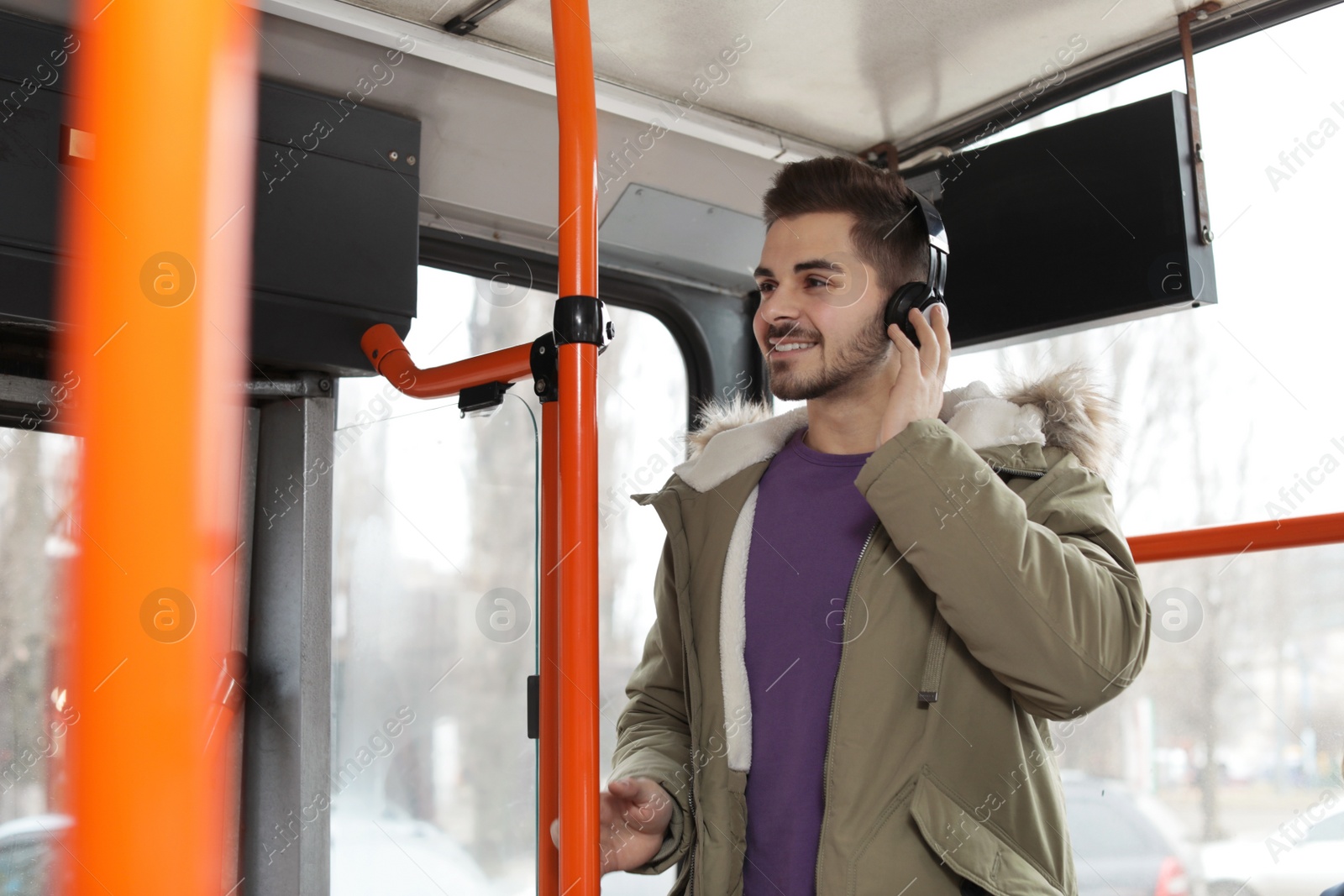 Photo of Young man listening to music with headphones in public transport