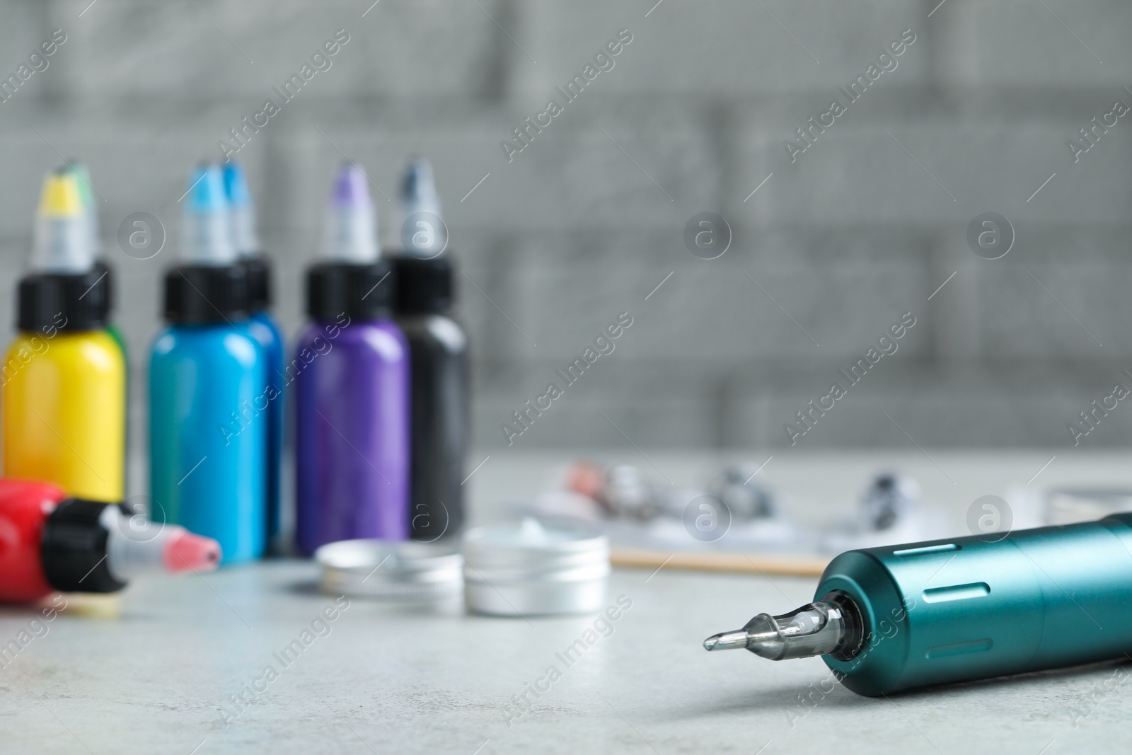 Photo of Modern professional tattoo machine and colorful inks on white table, space for text