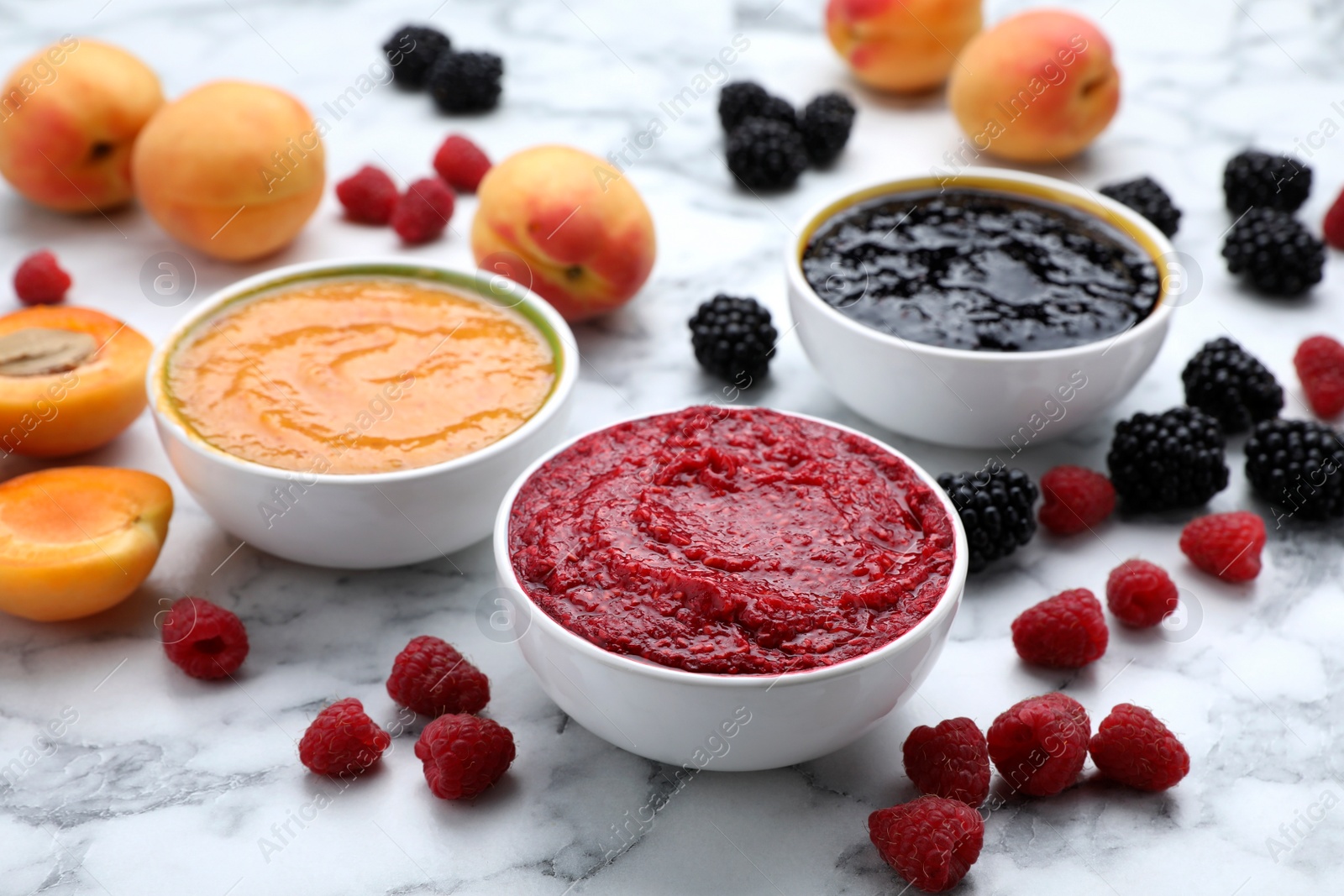 Photo of Different puree in bowls and fresh ingredients on white marble table