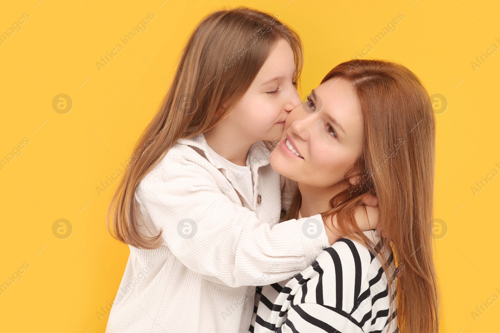 Photo of Portrait of happy mother and her cute daughter on orange background