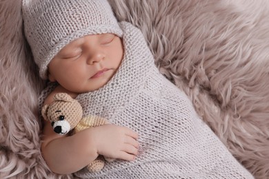 Photo of Adorable newborn baby with toy bear lying on faux fur