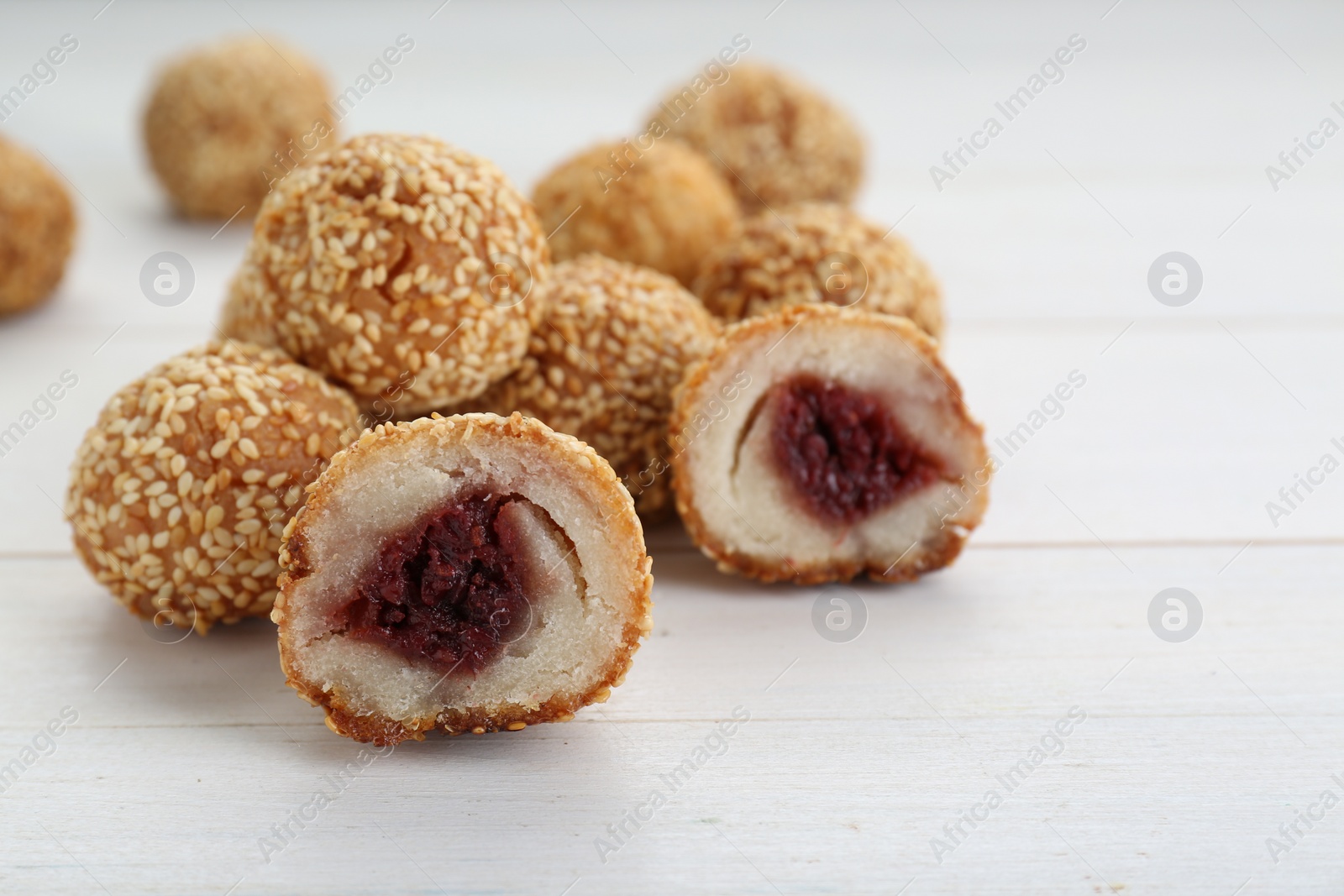 Photo of Delicious sesame balls with red bean paste on white wooden table, closeup