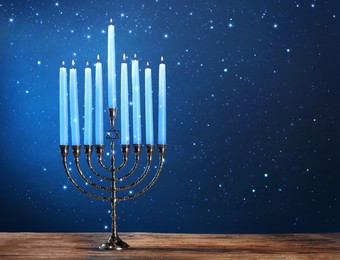 Image of Hanukkah celebration. Menorah with burning candles on wooden table against blue background, space for text