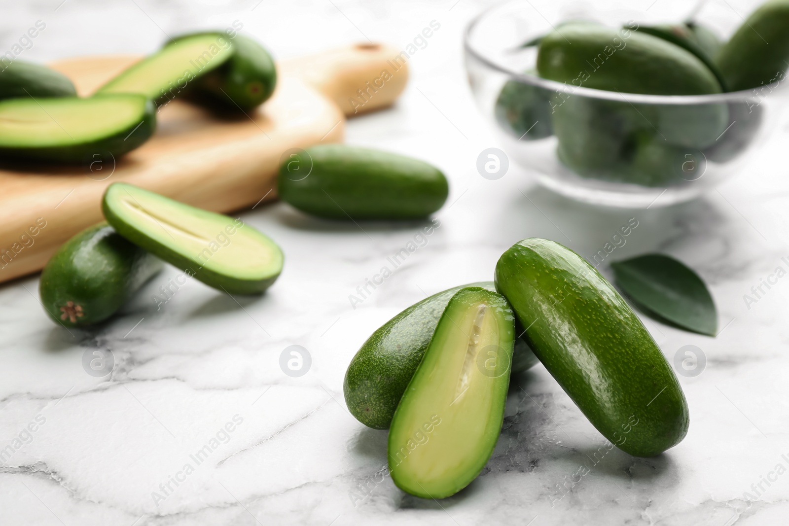 Photo of Fresh seedless avocados with green leaves on marble  table