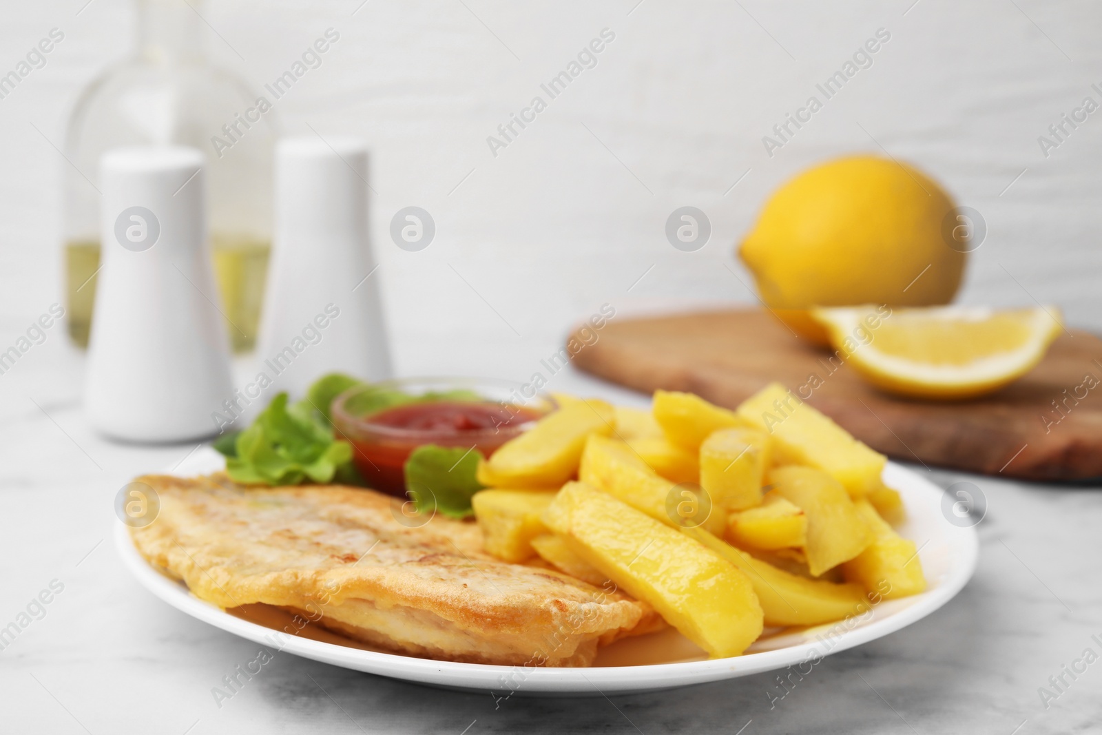 Photo of Delicious fish and chips with ketchup and lettuce on light table, closeup