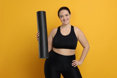 Photo of Happy overweight woman with yoga mat on orange background