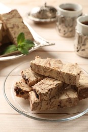 Photo of Pieces of tasty chocolate halva on wooden table