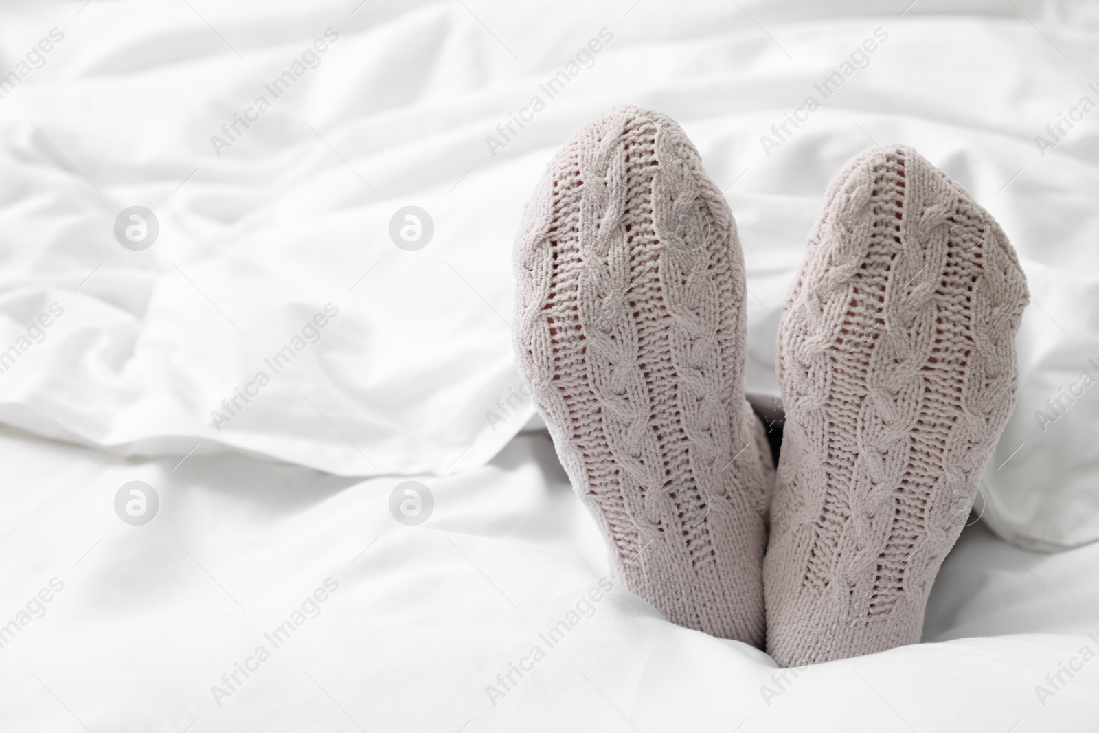 Photo of Woman in warm socks lying on bed, closeup. Space for text