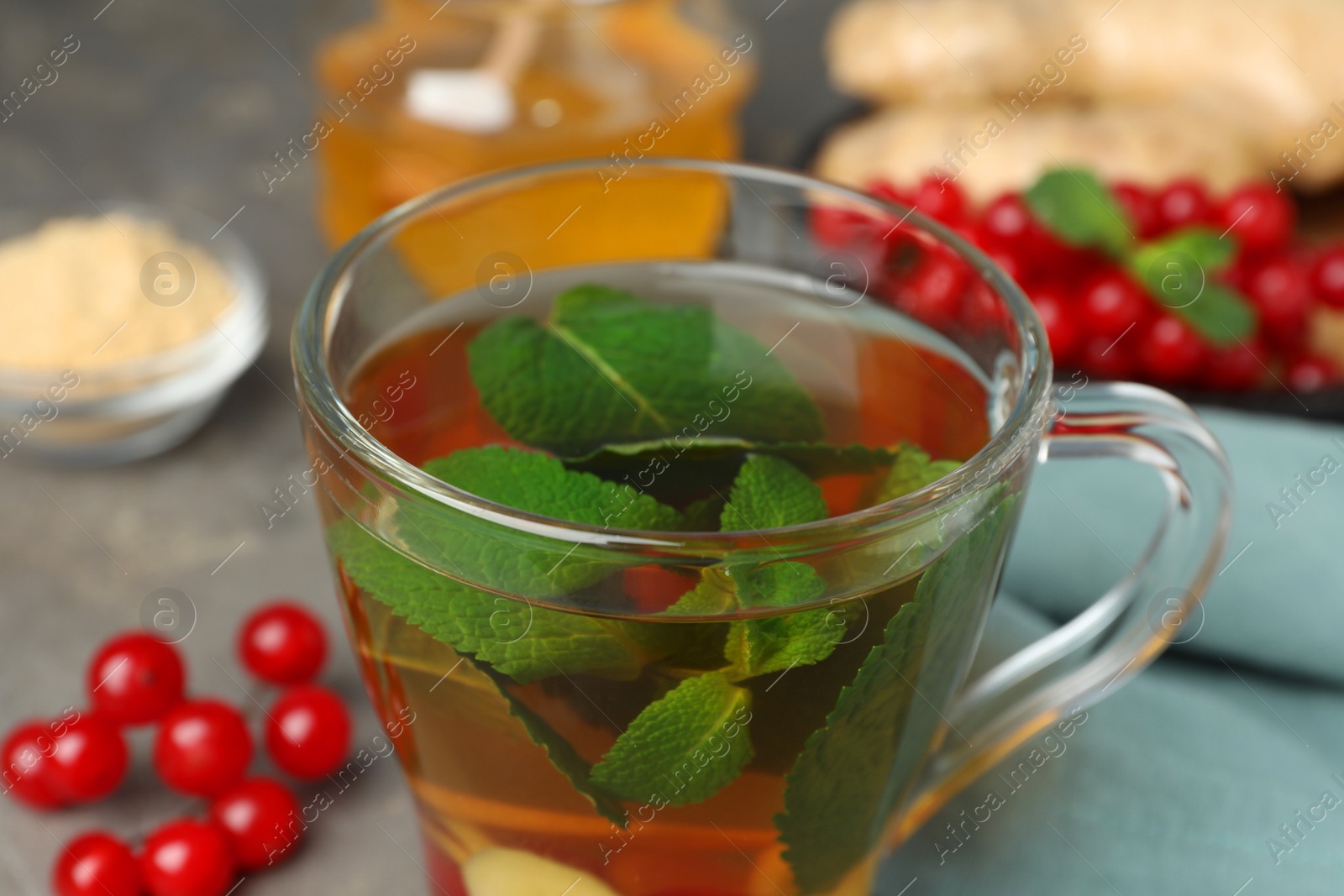 Photo of Glass cup of immunity boosting drink and ingredients on grey table, closeup