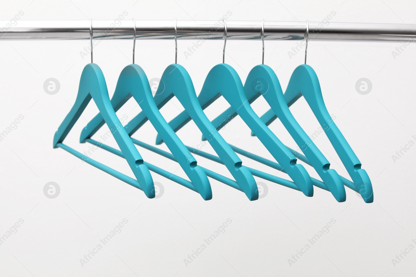 Photo of Clothes hangers on metal rail against light background