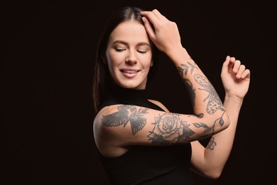 Photo of Beautiful woman with tattoos on arms against black background. Space for text
