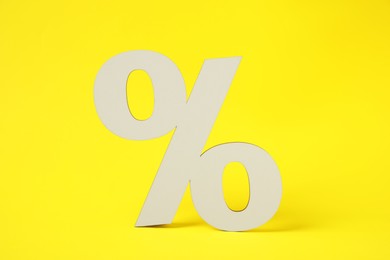 Photo of White wooden percent sign on yellow background