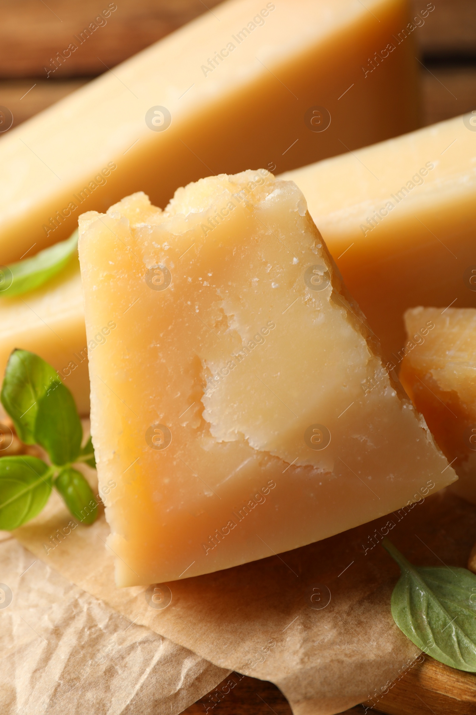 Photo of Delicious parmesan cheese with walnuts and basil on wooden table, closeup