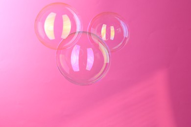 Photo of Beautiful transparent soap bubbles on pink background