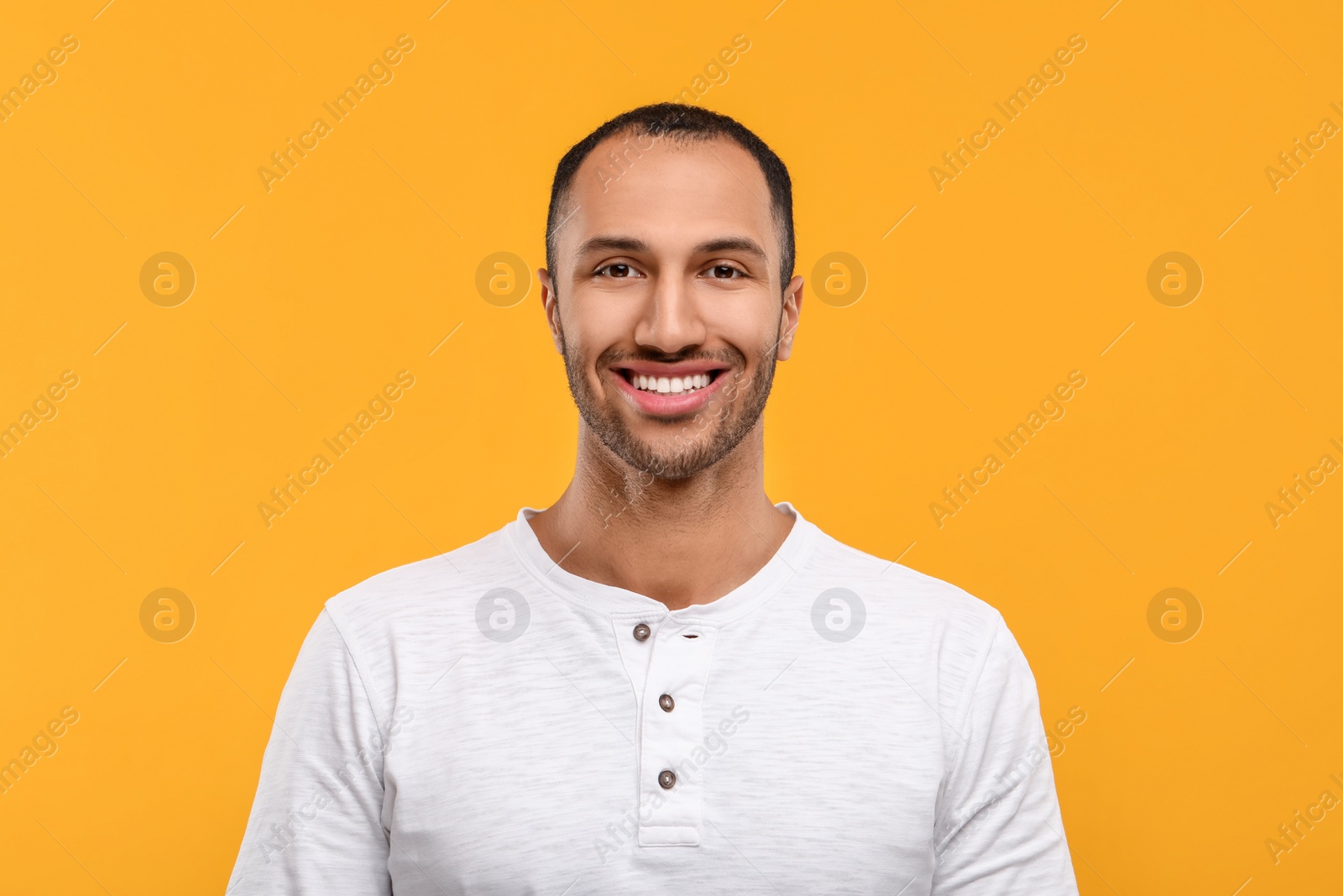 Photo of Portrait of smiling man with healthy clean teeth on orange background