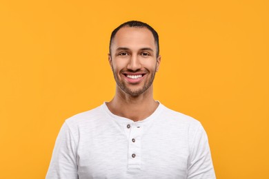Photo of Portrait of smiling man with healthy clean teeth on orange background