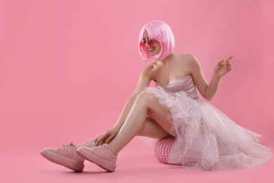 Photo of Pink look. Beautiful woman in dress and wig on color background, space for text