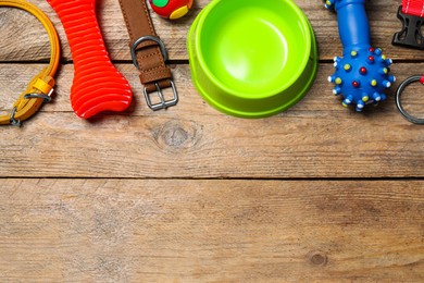 Flat lay composition with dog collar, toys and bowl on wooden table. Space for text