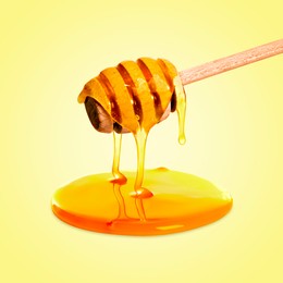 Image of Natural honey dripping from dipper on yellow background