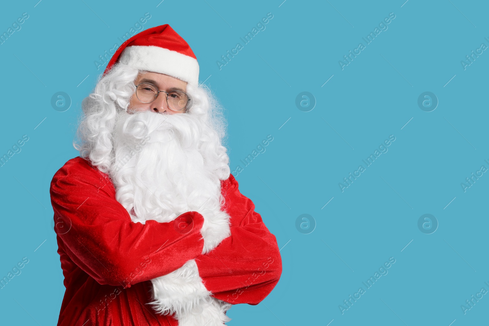 Photo of Merry Christmas. Santa Claus posing on light blue background, space for text