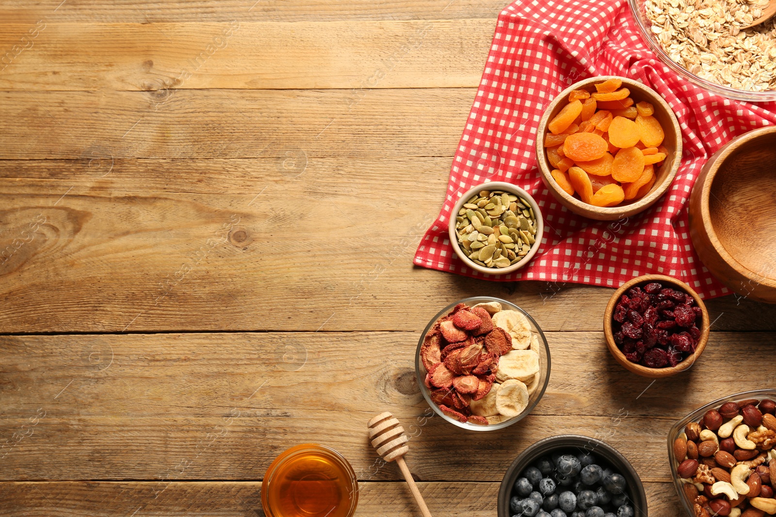 Photo of Making granola. Oat flakes, dried fruits and other ingredients on wooden table, flat lay with space for text