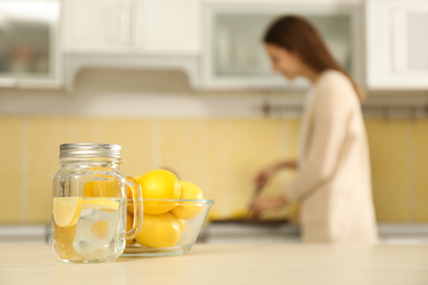 Photo of Mason jar with lemon water on table in kitchen