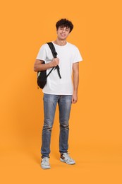 Photo of Handsome young man with backpack on orange background