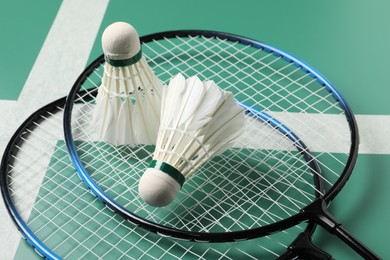 Photo of Feather badminton shuttlecocks and rackets on green table, closeup