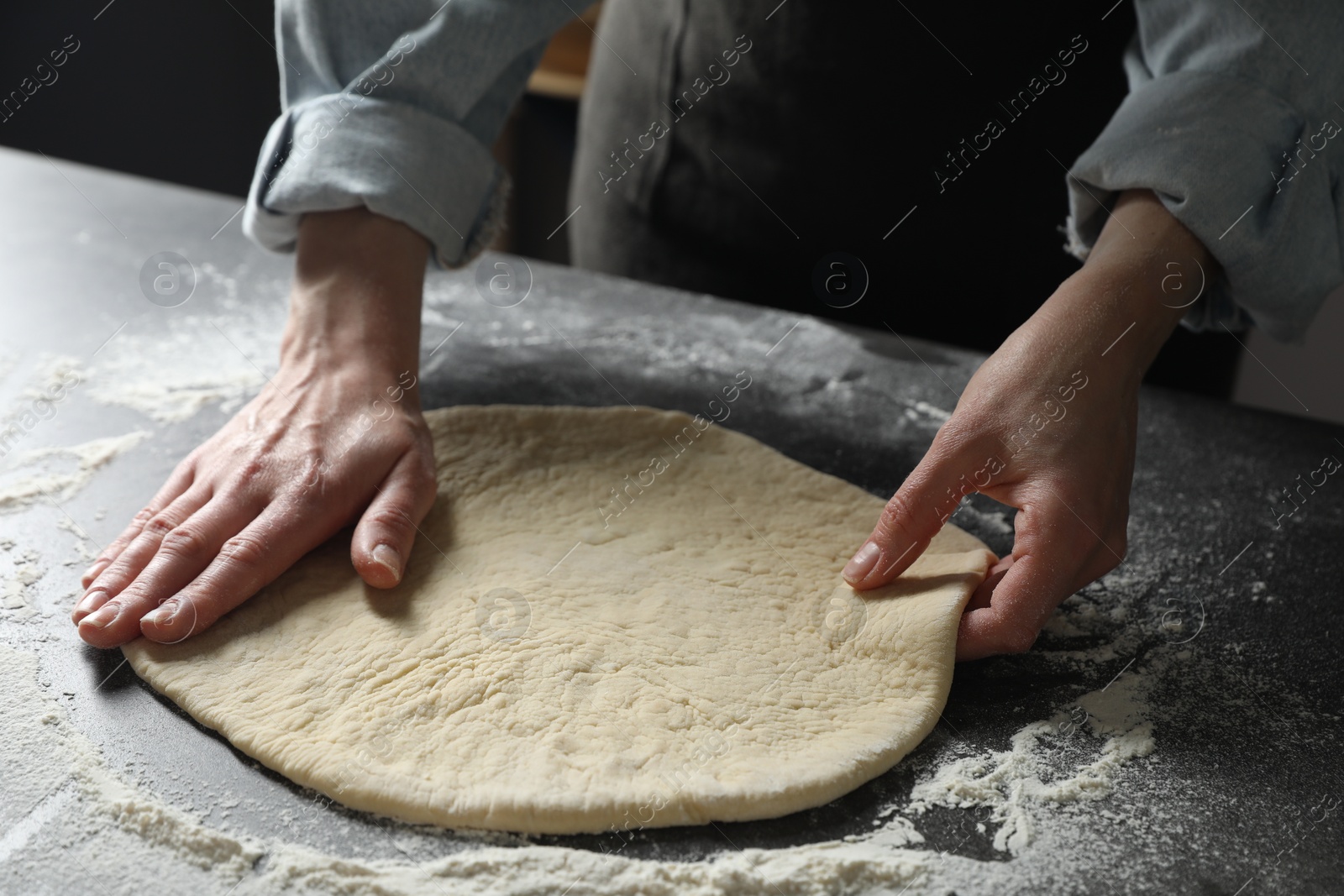 Photo of Woman making pizza dough at table, closeup