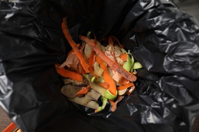 Photo of Garbage bin with peels of fresh vegetables, above view