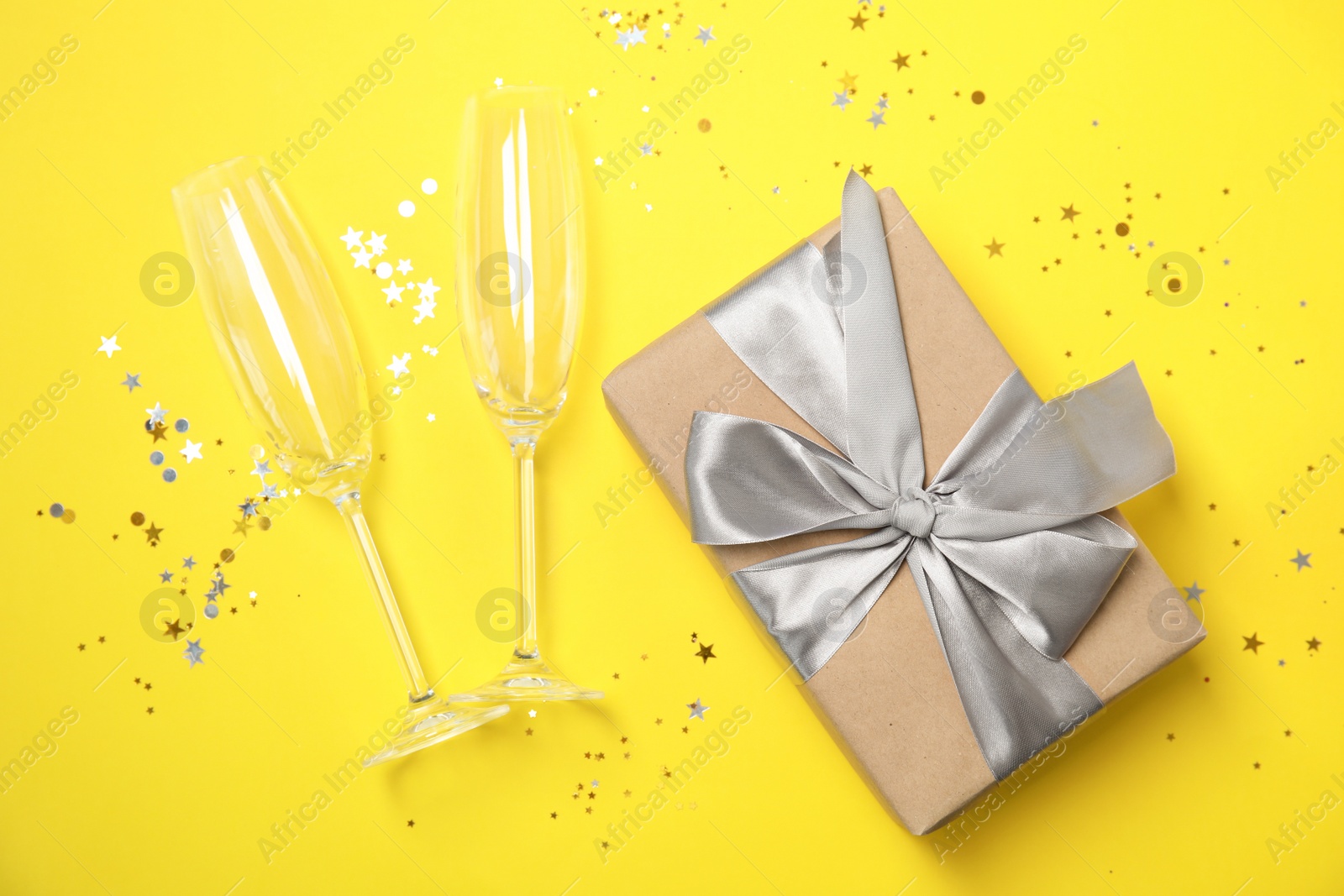 Photo of Creative flat lay composition with champagne glasses and gift box on color background