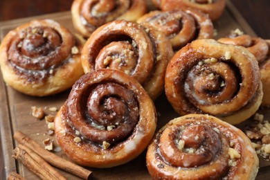 Photo of Tasty cinnamon rolls, sticks and nuts on table, closeup